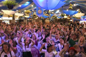 Público vestido com trajes típicos celebra a Schützenfest com mãos levantadas