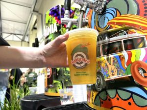 Chope da Schützenfest sendo servido em copo oficial com estampa colorida ao fundo