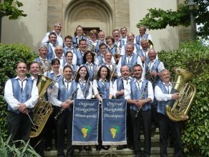 Integrantes da banda alemã Original Markgräfler Blaskapelle posando em escadaria antes de apresentação tradicional.
